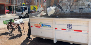 Foto que muestra una persona dejando residuos en un carro recolector