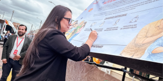 Foto de una mujer firmando una pancarta 