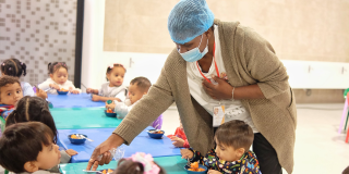 Imagen de una mujer atendiendo a niños y niñas en un comedor