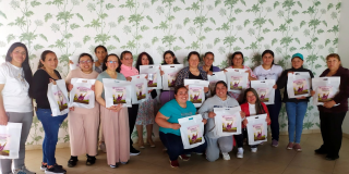 Foto de un grupo de mujeres posando con una bolsa blanca 