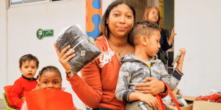 Imagen de una señora cargando a un niño y con una sudadera en la mano