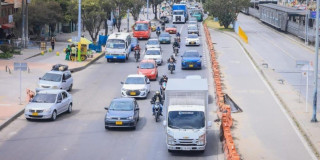 Foto que muestra vehículos andando por una vía de la ciudad 