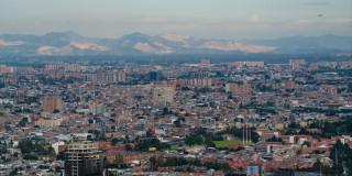 Vista panorámica de Bogotá con edificaciones extensas, montañas lejanas y cielo despejado