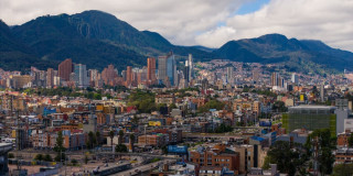 Vista panorámica de Bogotá con edificios residenciales, zona financiera y cerros orientales bajo cielo parcialmente nublado