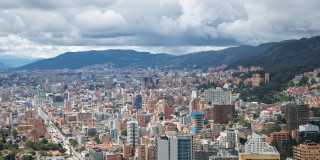 Vista panorámica de Bogotá con edificaciones, montañas orientales y cielo nublado amplio