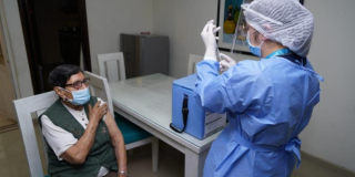Imagen de una enfermera aplicando una vacuna a una mujer mayor que usa tapabocas