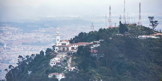 Vista del Santuario de Monserrate en cerro boscoso con ciudad de Bogotá al fondo