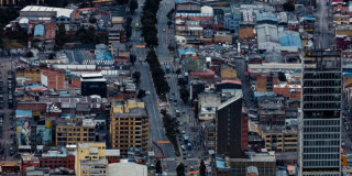 Vista aérea de avenida central de Bogotá con edificaciones densas y tráfico moderado