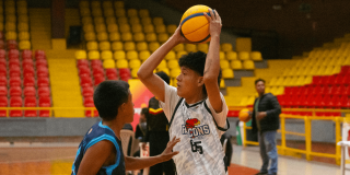 Jóvenes disputan partido de baloncesto en escenario deportivo cubierto de Bogotá.
