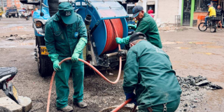 Imagen de tres técnicos de la empresa de Acueducto realizando mantenimiento en un tubo de alcantarillado.