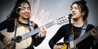 Imagen de Briela Ojeda e Isabel Ramírez “La Muchacha” tocando guitarras en concierto.