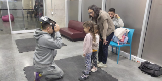 Imagen de un niño arrodillado jugando con lentes 3D mientras dos niñas y una mujer lo observan