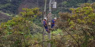Foto que muestra dos personas con uniformes de Enel Colombia trabajando en un poste de luz