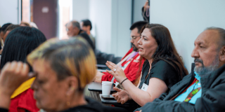 Mujer en el público de un evento o charla, hablando.