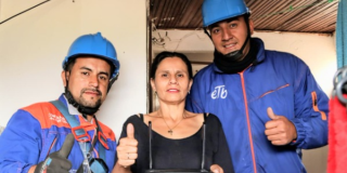 Imagen de dos operarios de etb junto a una señora sonriendo
