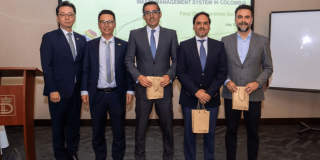 Foto que muestra cinco hombres en un auditorio sonriendo 