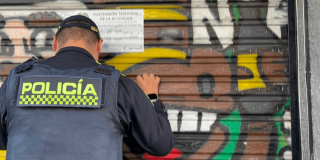 Policía pegando un aviso de suspensión temporal en un establecimiento del Siete de Agosto