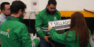 Personal de entidades distritales realiza procedimiento de control ambiental en establecimiento. Una funcionaria sostiene aviso con texto que dice “SELLADO”, mientras otros funcionarios participan en la diligencia de inspección y cierre.