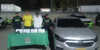 Dos de los capturados con material incautado y uno de los carros recuperados.