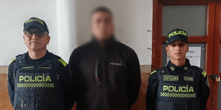 Hombre capturado por hacer 'cambiazos' de tarjetas, en medio de dos uniformados.