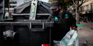 Foto que muestra una persona sacando residuos de un contenedor de basura