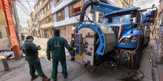 Foto que muestra trabajadores del Acueducto de Bogotá junto a un carro 