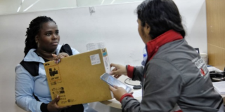 Imagen de una funcionaria entregando un computador a una mujer