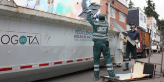 Foto que muestra dos personas dejando residuos en un carro recolector