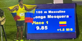 Ronal Longa celebra victoria 100 metros con bandera y marcador electrónico iluminado