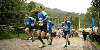 Participantes corren por el sendero empedrado de Monserrate rodeados de vegetación y público asistente.