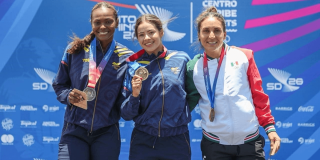Gabriela Rueda exhibe su medalla de oro durante ceremonia de premiación de los Juegos Centroamericanos y del Caribe Santo Domingo 2026, frente al panel oficial del evento deportivo.