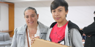 Imagen de Yasmín sonriendo junto a su hijo quien carga el computador