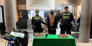 Hombre capturado, en medio de dos policías, junto a material incautado y recuperado.