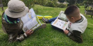Imagen de niños leyendo libros al aire libre en un parque de Bogotá.