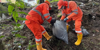 Foto que muestra dos personas con el uniforme de Aguas de Bogotá recogiendo residuos