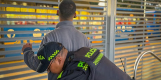 Un policía requisando a un ciudadano en una estación de TransMilenio.