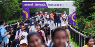 Visitantes recorren el sendero de Monserrate en Bogotá entre zonas verdes y barandas de madera, junto a un pórtico con el texto: “Gracias por visitar el sendero de Monserrate”.