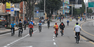 Ciclistas recorren una avenida de Bogotá durante la Ciclovía, utilizando los carriles habilitados para bicicletas.