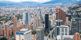 Vista panorámica de Bogotá con torres residenciales y empresariales, corredores viales, alta concentración de edificaciones y cerros orientales al fondo.
