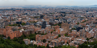 Vista panorámica de Bogotá con edificios residenciales y comerciales de mediana altura, zonas arboladas en primer plano y extensa expansión urbana hacia el horizonte.