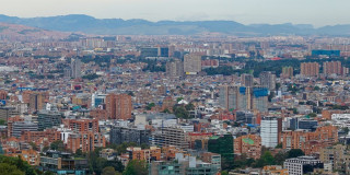 Vista panorámica de Bogotá con edificaciones residenciales y comerciales, cerros orientales al fondo y paisaje urbano.