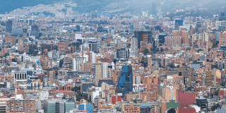 Vista panorámica de Bogotá con edificios residenciales y comerciales, centro financiero, cerros orientales y cielo parcialmente nublado.