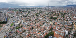 Vista aérea de Bogotá con amplia zona residencial, avenidas principales y numerosos edificios de baja y mediana altura, bajo cielo nublado con cerros visibles al fondo