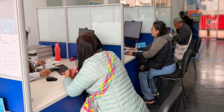 Foto que muestra tres personas sentadas frente a modulos de atención 