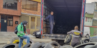 Foto que muestra personas recolectando llantas y colocandolas en un camión 
