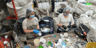 Foto que muesta dos personas con tapabocas y guantes separando residuos
