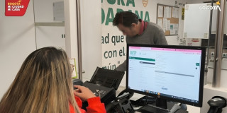 Foto que muestra dos personas hablando y un computador 