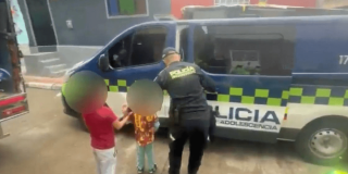 Dos niños rescatados, de la mano con un policía.