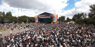 Miles de personas asisten al parque Simón Bolívar de Bogotá, reunidas frente a un escenario principal de gran formato durante un espectáculo musical al aire libre.