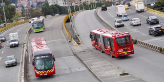 Foto de una vía de Bogotá donde se ven varios buses de TransMilenio.
